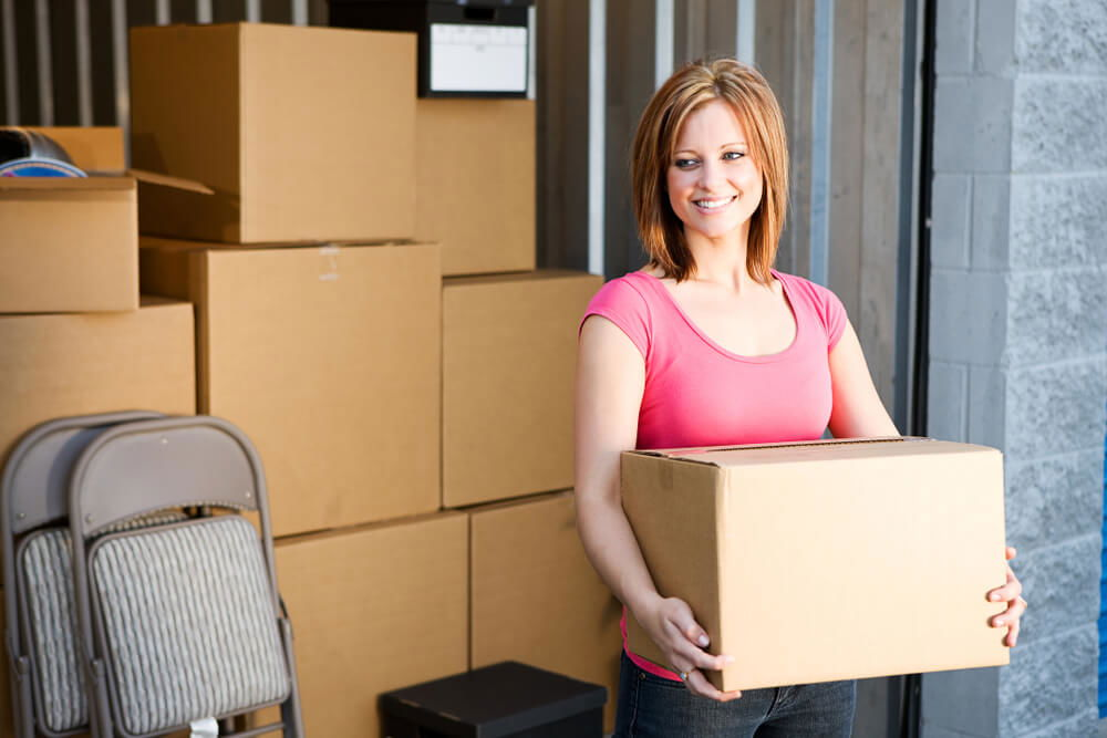 Woman Holding Boxes in front of a Storage Unit
